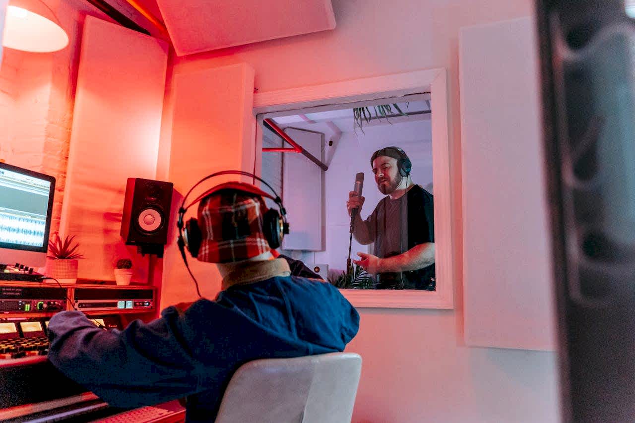 Audio engineer and singer collaborating in a modern recording studio environment.