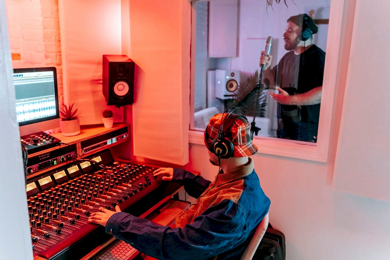Two men engaged in a vocal recording session in a modern music studio, highlighting sound equipment.